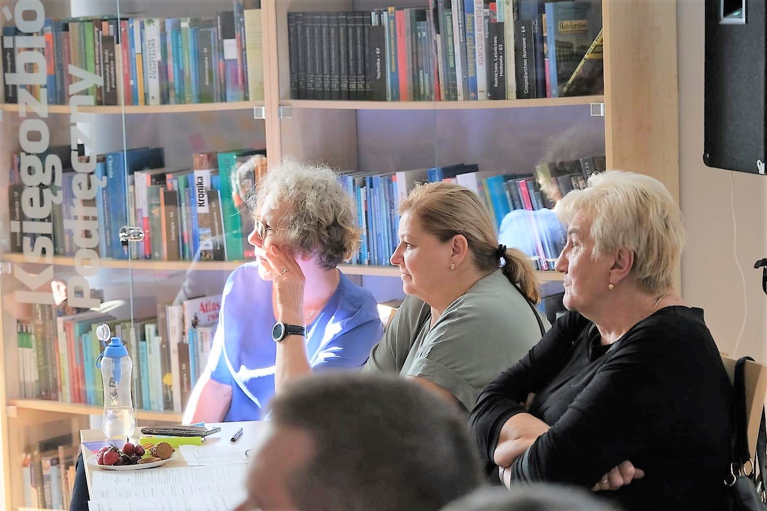 Trzy osoby na warsztatach w przestrzeni biblioteki miejskiej